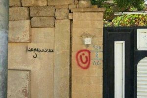 Huruf N dalam alfabet Arab, berarti Nasrani. Ini adalah tanda yang dipasang ISIS di rumah-rumah orang Kristen Mosul untuk dijarah dan penghuninya dipaksa menganut Islam, diusir, dipasang pajak tinggi, atau dibunuh!